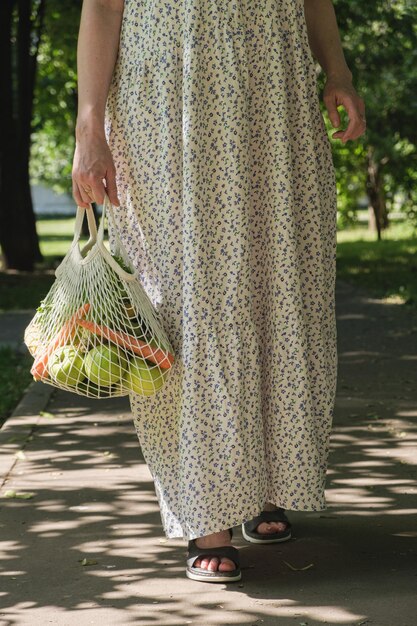 Borsa a rete lavorata a maglia con frutta e verdura nelle mani di una donna