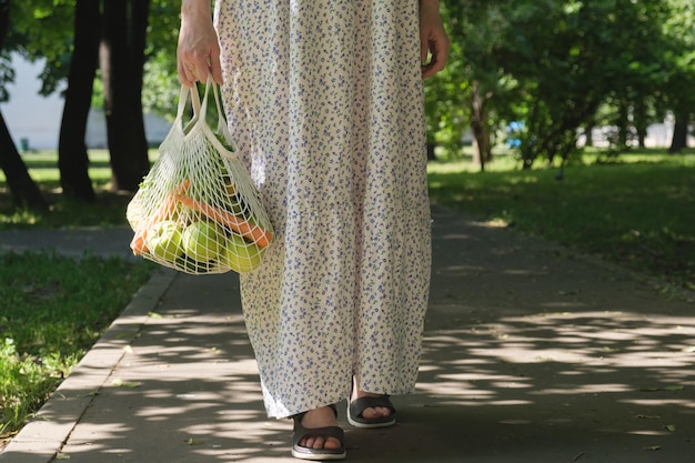 Borsa a rete lavorata a maglia con frutta e verdura nelle mani di una donna