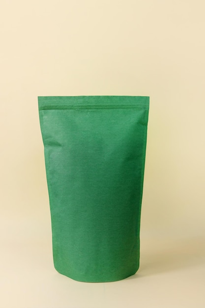 Borsa a sacchetto verde mockup sfondo beige neutro monocromatico Confezione di carta riciclata verde smeraldo vuota spazio per la copia dei chicchi di caffè