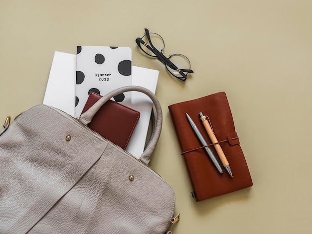 Borsa da donna con accessori per la formazione aziendale in ufficio su sfondo giallo vista dall'alto