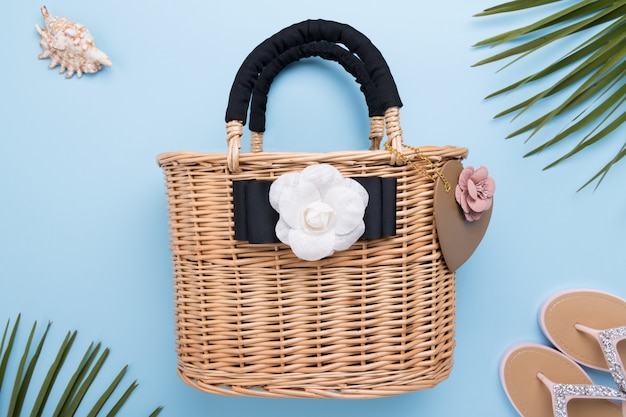 Borsa da donna in vimini moda su superficie blu pastello chiaro, primi piani, concetto di viaggio e vacanze, vista dall'alto, concetto di estate