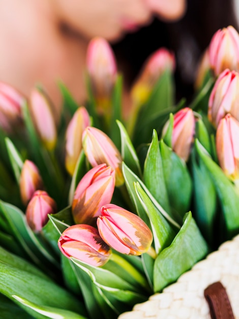 Borsa della paglia della tenuta della donna con il mazzo di tulipani rosa freschi