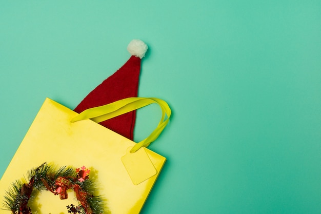 Borsa della spesa gialla vista dall'alto con cappello di babbo natale sul tavolo con le festività natalizie