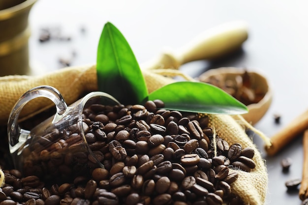 Borsa di caffè. Chicchi di caffè tostati sul tavolo. Chicchi di caffè con foglie verdi per cucinare.