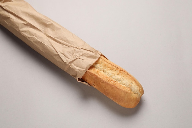 Borsa di carta con baguette fresca su sfondo beige vista dall'alto