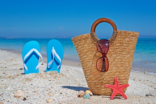 Borsa di paglia conchiglie seastar e sandali in riva al mare