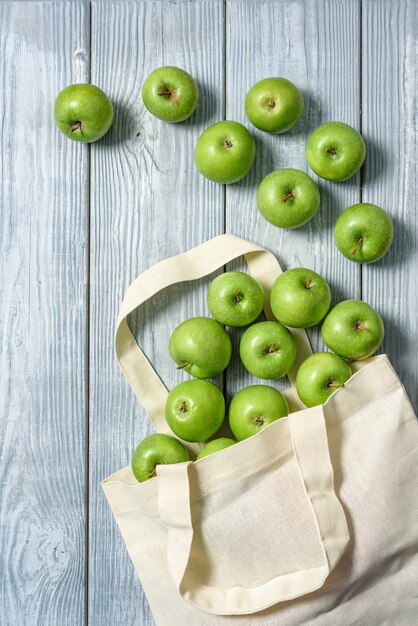 Borsa di stoffa con mele verdi su un tavolo di legno. Shopping bag zero rifiuti con frutta.