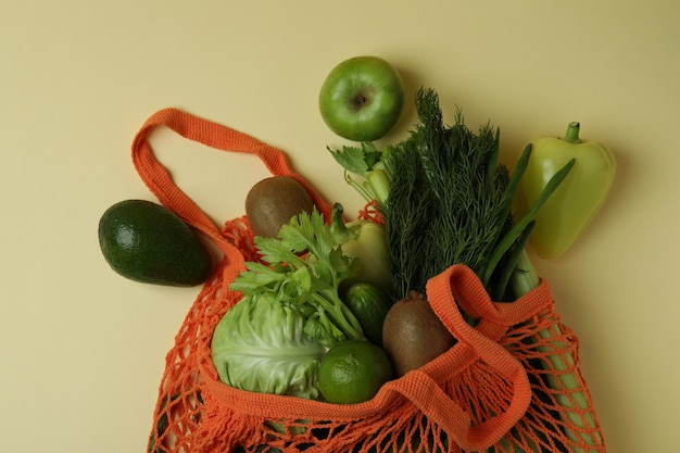 Borsa di stringa con verdure verdi su fondo beige