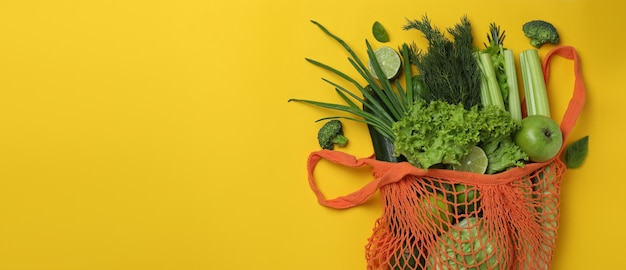 Borsa di stringa con verdure verdi su sfondo giallo