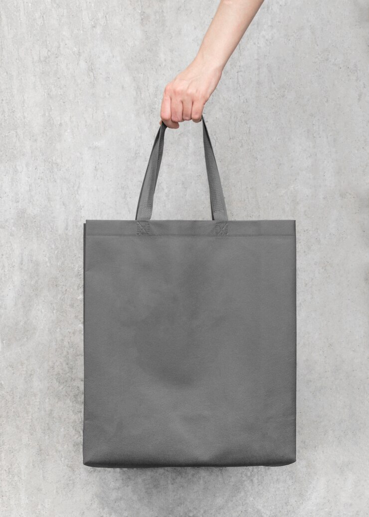 Borsa di tela grigia in bianco su sfondo di muro di cemento, design mock up con mano. Borse per lo shopping.