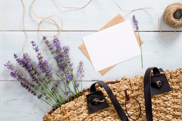 Borsa donna con fiori di lavanda, carta di carta bianca e busta sullo scrittorio di legno blu