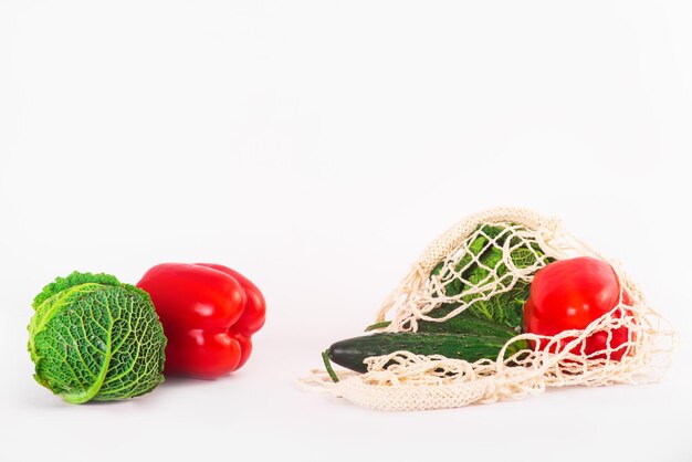 Borsa ecologica in tela di cotone con verdure biologiche e alimenti su sfondo bianco. Zero sprechi, concetto plastic free. Vista dall'alto, distesa