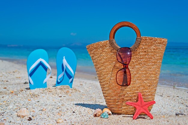 Borsa in paglia da riva con sandali blu sullo sfondo