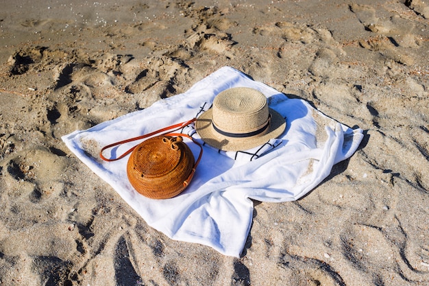 Borsa intrecciata moderna delle donne sulla pavimentazione bianca sulla spiaggia