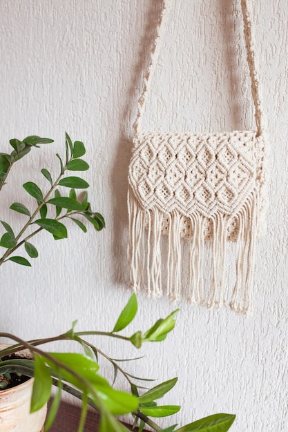 Borsa macramè fatta a mano sulla parete leggera Borsa in cotone macramè naturale ecologico Hobby lavoro a maglia macramè fatto a mano Concetto estivo moderno Copia spazio