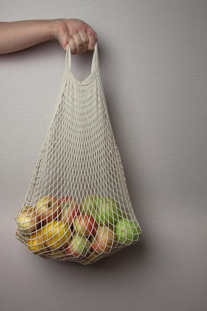 Borsa per la spesa in rete con frutta biologica colorata in mano femminile senza rifiuti concetto riutilizzabile