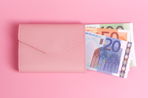 borsa rosa su sfondo rosa pastello con banconote in euro dentro