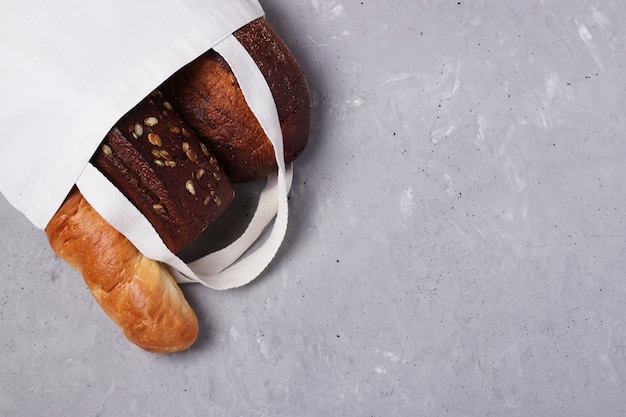 Borsa shopping in tessuto di cotone riutilizzabile fatta a mano con pane fresco su cemento grigio