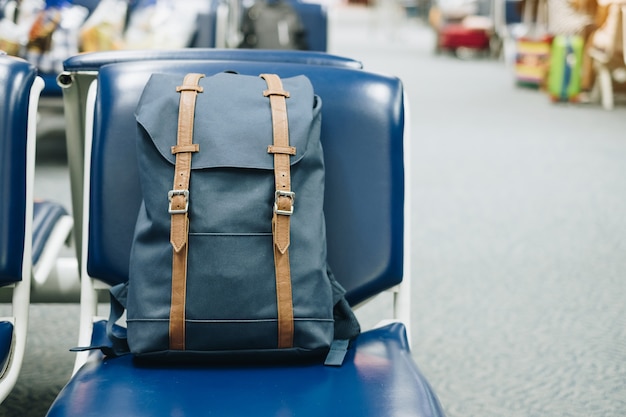 Borsa vintage blu sul sedile all&#39;interno del terminal dell&#39;aeroporto. Viaggia e torna al concetto di scuola