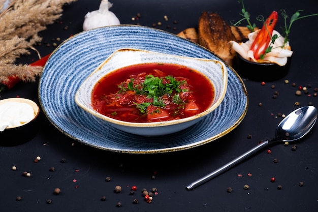 Borsch piatto nazionale ucraino con pane scuro e aglio su una superficie scura