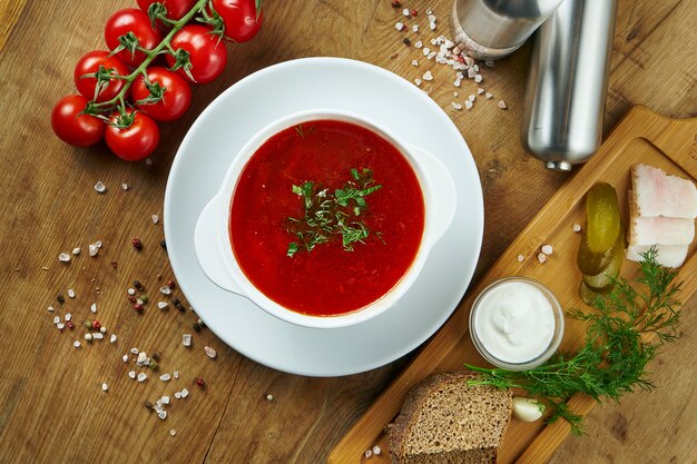 Borsch ucraino fatto in casa e gustoso con panna acida in una ciotola su una superficie di legno