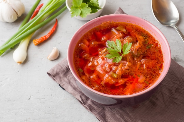 Borsch, zuppa di barbabietola in una ciotola di legno con erbe fresche