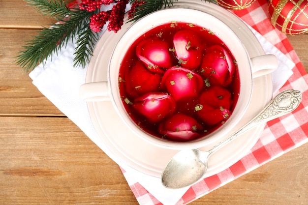 Borscht rosso chiaro polacco tradizionale con gnocchi e decorazioni natalizie sulla superficie del tavolo in legno