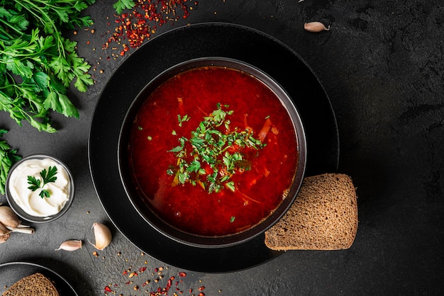 Borscht russo ucraino tradizionale su sfondo scuro. Borscht con panna acida. Borscht di barbabietola con prezzemolo. Foto di alta qualità