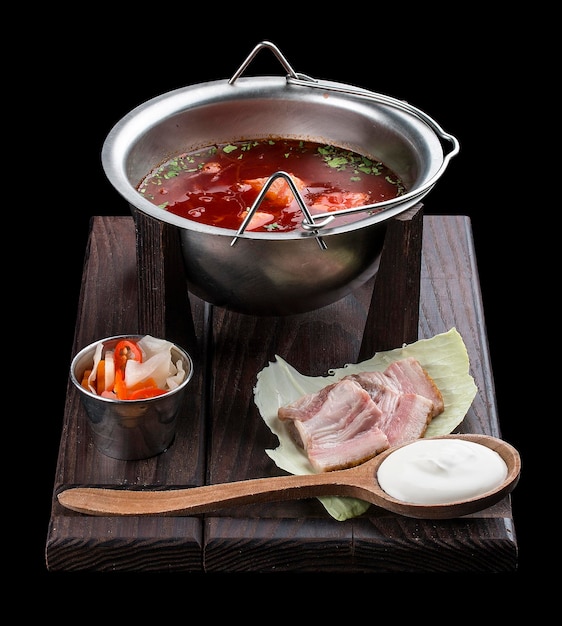 Borscht ucraino con pancetta alla panna acida e snack piccanti su una tavola di legno su sfondo scuro