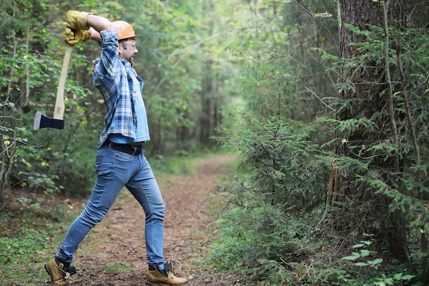 Boscaiolo maschio nella foresta Un taglialegna professionista ispeziona gli alberi per l'abbattimento