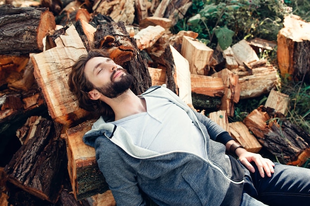 Boscaiolo stanco che dorme sul mucchio di legno.