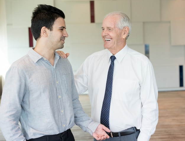 Boss sorridente che schiaffeggia giovane collega sulla spalla