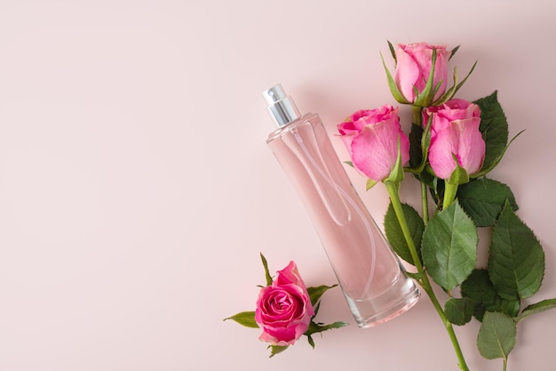 Bottiglia chic di profumo femminile con delicate rose rosa su sfondo pastello Vista superiore Uno spazio di copia Modello di bottiglia vuota Presentazione del prodotto