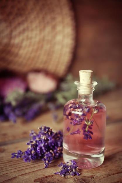 Bottiglia con olio aromatico e fiori di lavanda su fondo di legno