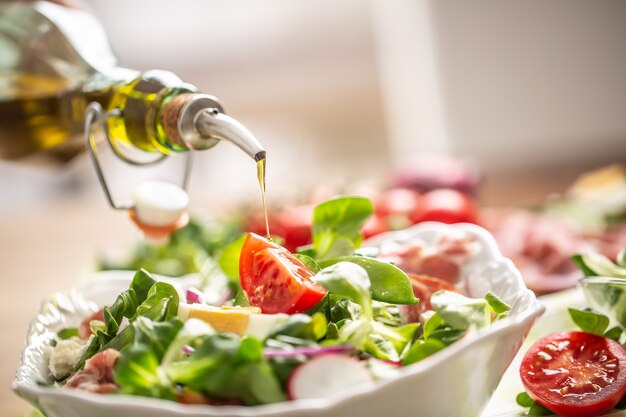 Bottiglia con olio d'oliva che si versa nell'insalata.