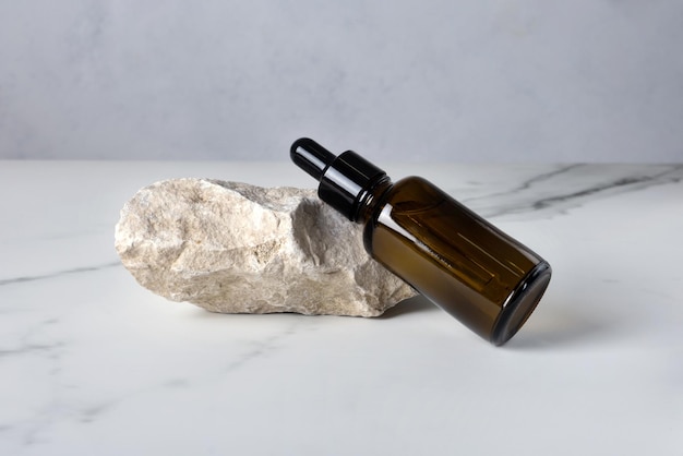 Bottiglia con una pipetta con un prodotto cosmetico su una pietra