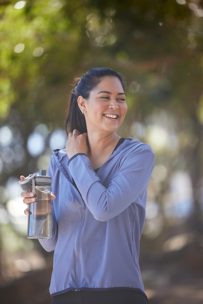 Bottiglia d'acqua della foresta e donna con alimentazione fitness e obiettivi salutari per la dieta del corpo benessere all'aperto e stile di vita escursionistico Atleta sportivo e donna felice che bevono acqua durante un allenamento nei boschi