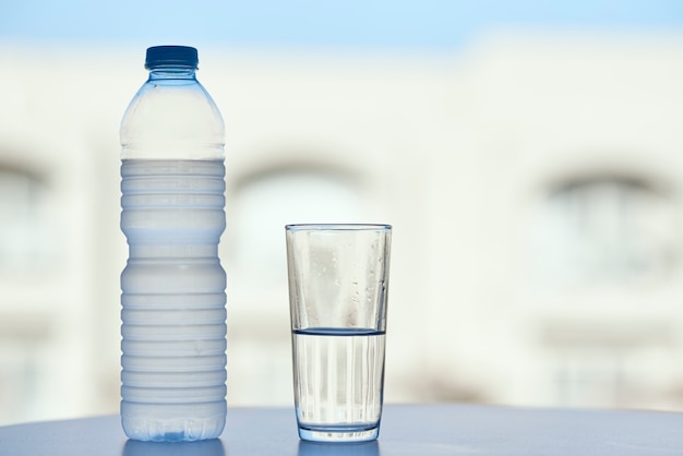 Bottiglia d'acqua e bicchiere d'acqua sul tavolo