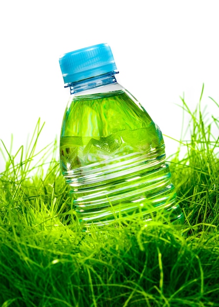 Bottiglia d'acqua sull'erba verde isolata su sfondo bianco