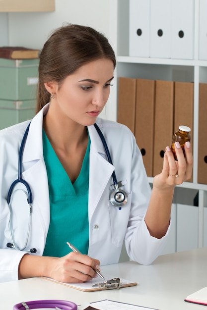Bottiglia della holding del medico femminile con le pillole e prescrizione di scrittura