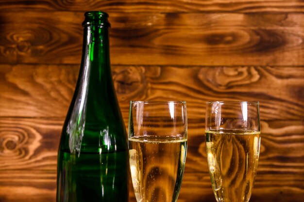 Bottiglia di champagne e due bicchieri da vino su tavola di legno rustica