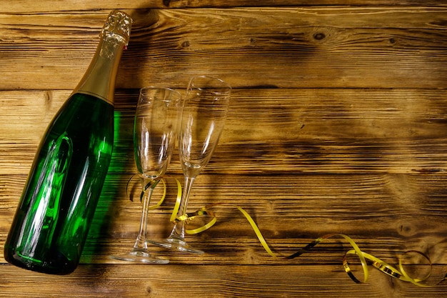 Bottiglia di champagne e due bicchieri di champagne vuoti su sfondo di legno Spazio per la copia della vista dall'alto