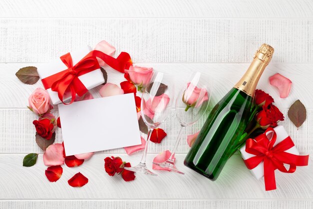 Bottiglia di champagne e petali di fiori di rosa carta di auguri per il giorno di San Valentino con scatole regalo e spazio per i vostri saluti