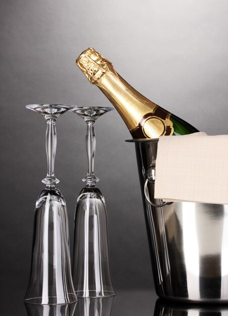 Bottiglia di champagne nel secchiello con ghiaccio e bicchieri