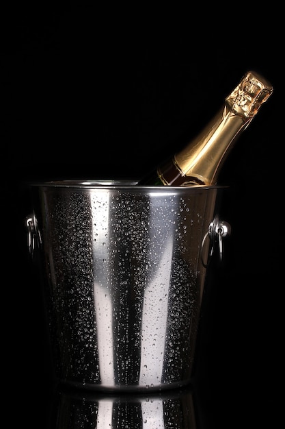 Bottiglia di champagne nel secchio isolato su nero