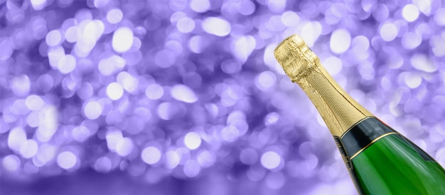 Bottiglia di champagne su sfondo lilla scintillante con bokeh illuminato Banner di Capodanno