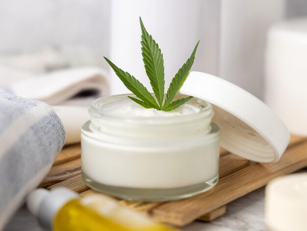 Bottiglia di crema aperta con foglie di cannabis verde chiusa cosmetico organico naturale CBD