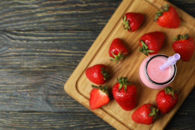 Bottiglia di frullato alla fragola e ingredienti sul tavolo di legno