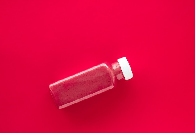 Bottiglia di frullato di fragole superfood disintossicante per la pulizia della perdita di peso su sfondo rosso design piatto per blog di esperti di cibo e nutrizione