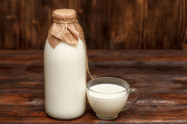 Bottiglia di latte e tazza sulla tavola di legno rustica